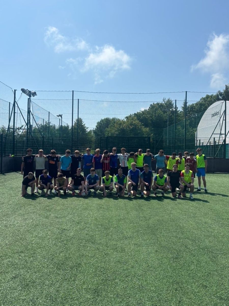 A large group of players posing on the pitch on a sunny day