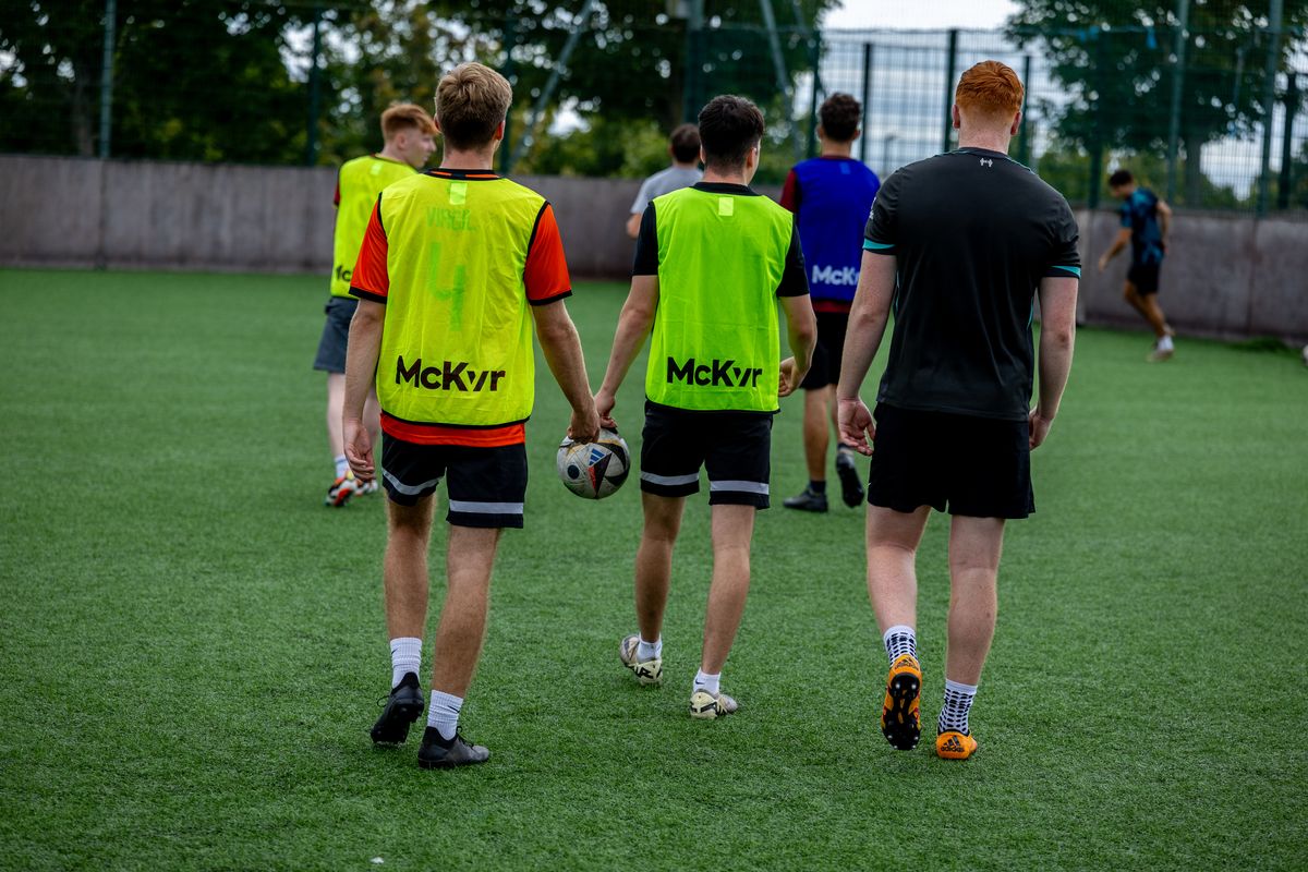 Players in RIVALZ bibs walking onto the pitch with the ball
